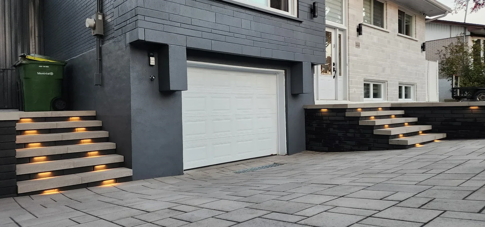 Paved courtyard with broad steps beside a grey home